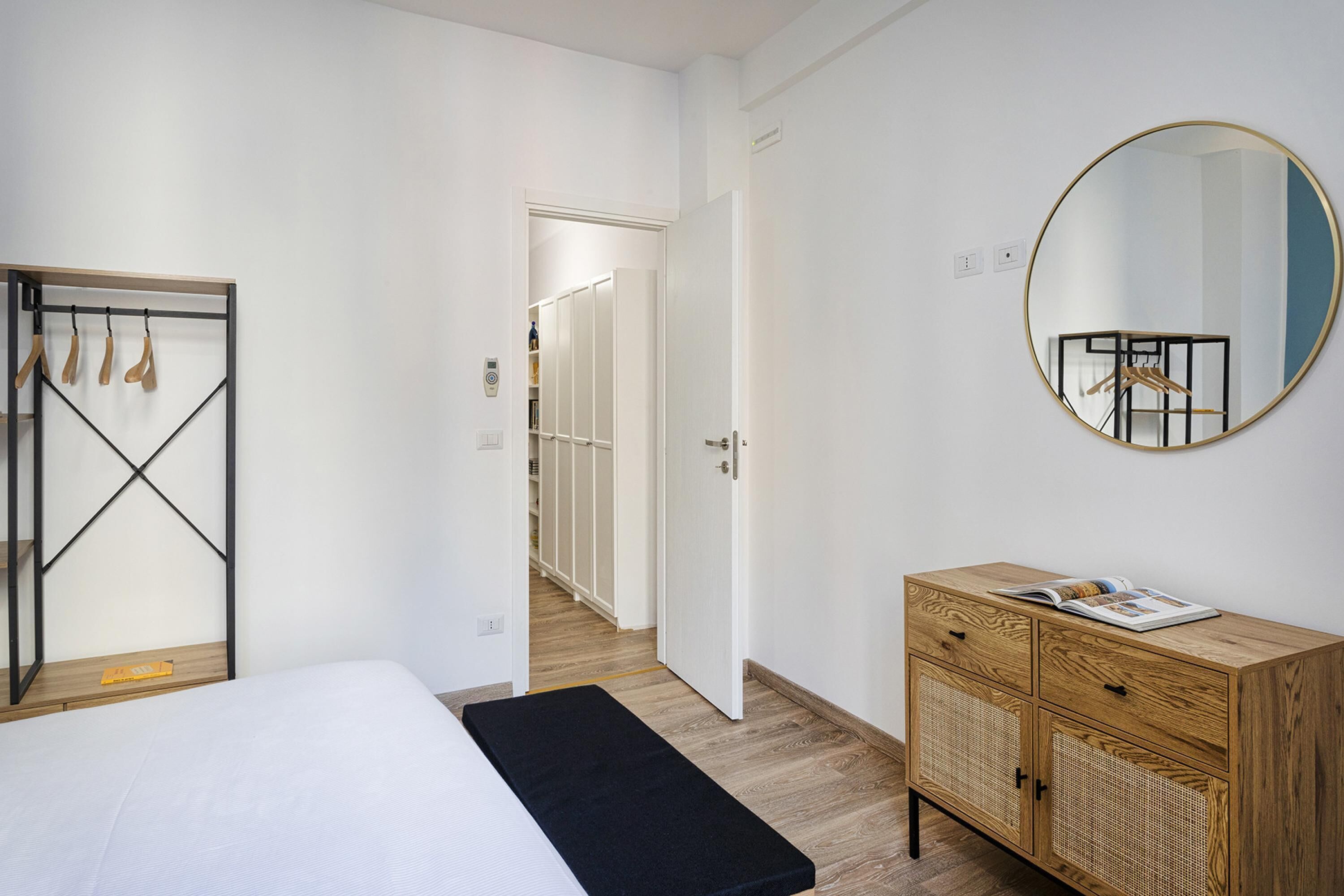 Ein Schlafzimmer mit einem Bett, einer Holzkommode, einem Spiegel und einem Kleiderschrank.