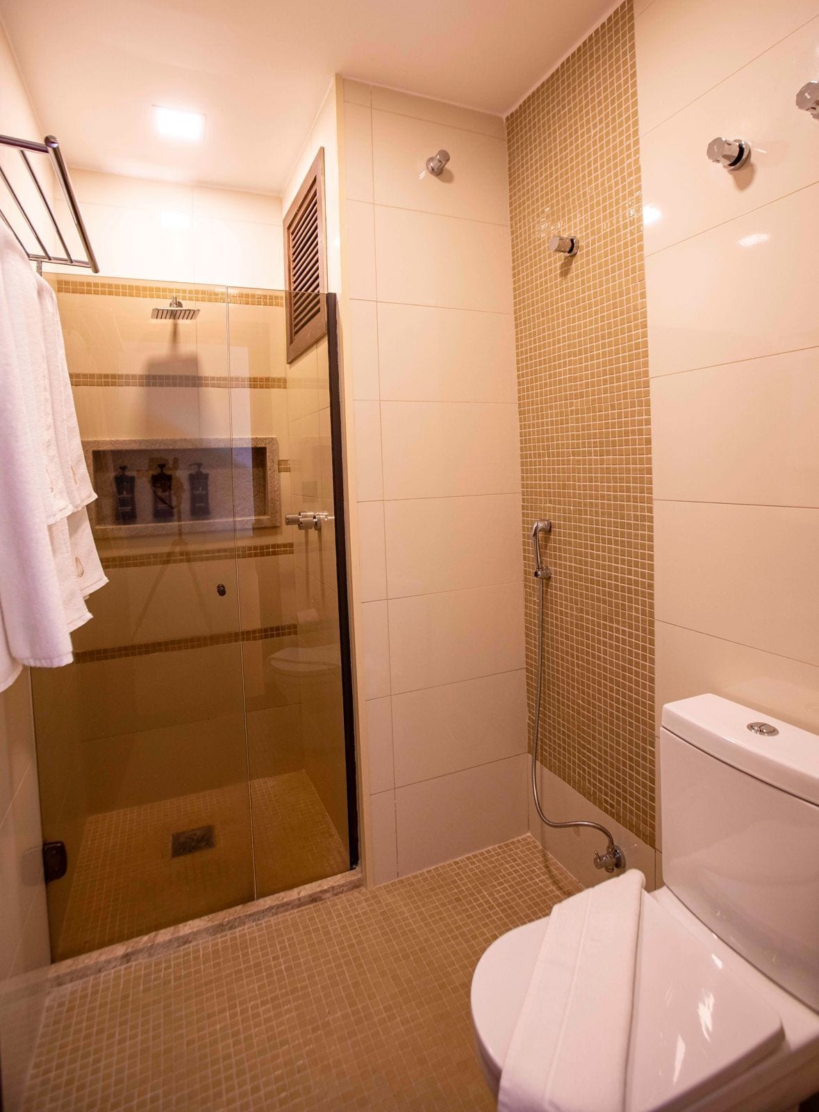 A bathroom with a glass-enclosed shower, a toilet, and a sink.