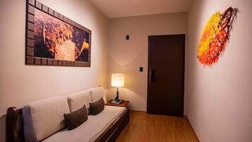 A modern room with a sofa, a wall-mounted artwork, a lamp, and a door.