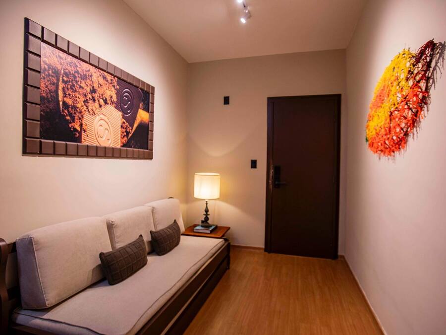 A modern room with a sofa, a wall-mounted artwork, a lamp, and a door.