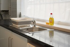 A kitchen with a stainless steel sink, a dish rack, and a bottle of dish soap on the counter. - Peaceful Grimsby House w/ Fast WiFi & Garden (Grimsby)
