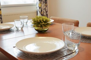 A dining table with plates, glasses, and a decorative plant.