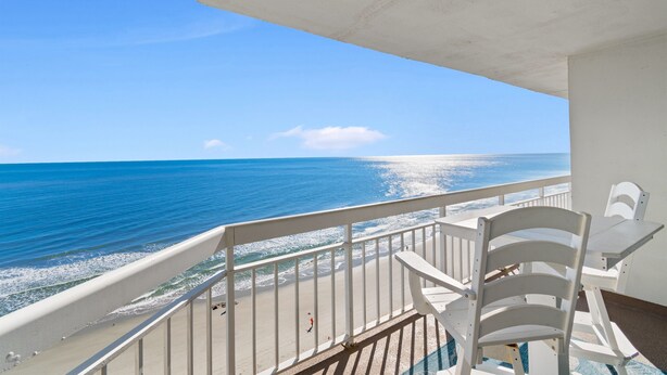 A balcony with a view of the ocean, white chairs, and a table. - Garden City Beach Oceanfront Condo 912 | Rising Tides Properties Rental (Murrells Inlet)