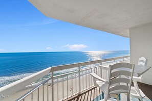 A balcony with a view of the ocean, white chairs, and a table. - Garden City Beach Oceanfront Condo 912 | Rising Tides Properties Rental (Murrells Inlet)