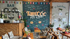 A cozy cafe with wooden furniture, a chalkboard menu, and a variety of plants. - Vi TamCoc Hotel (Nam Hoa Lu)