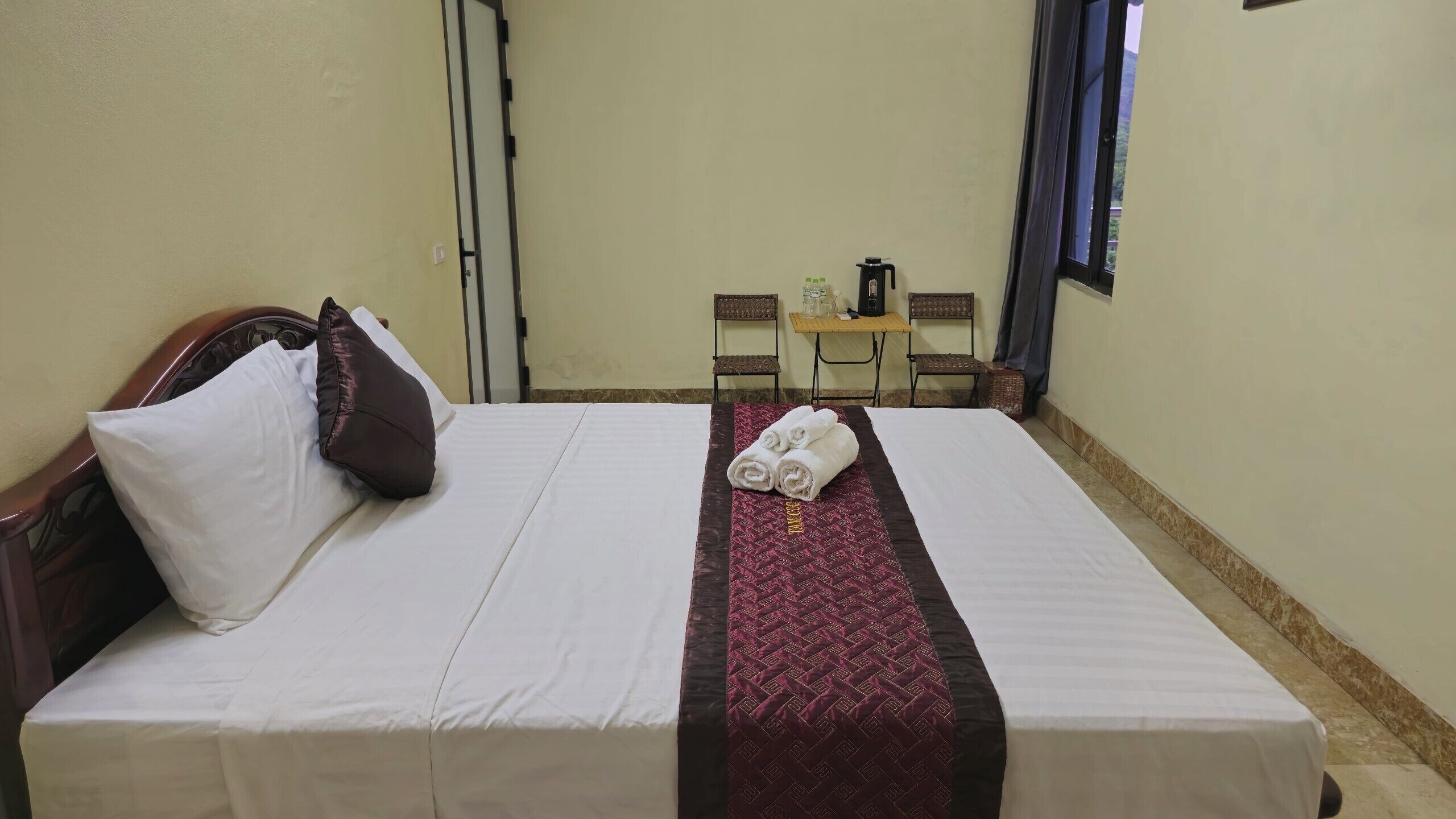Ein Hotelzimmer mit einem Bett, einem kleinen Tisch mit einer Kaffeemaschine und einem Fenster mit Vorhängen.