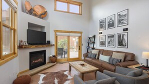 Ein modernes Wohnzimmer mit Kamin, Fernseher, Sofa und Couchtisch.