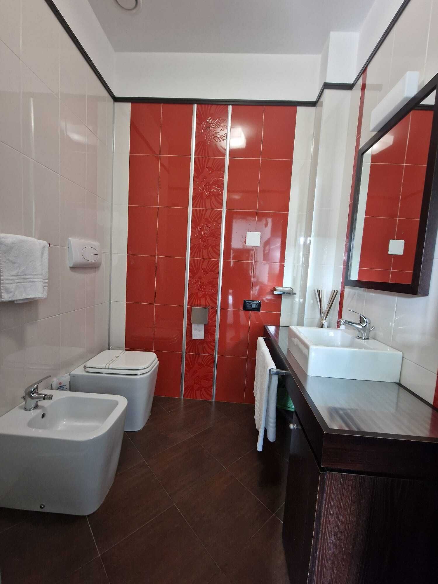 Un baño moderno con inodoro blanco, un bidé, un lavamanos y un espejo grande.