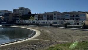 Zona costera con edificios a lo largo de la orilla, una playa de arena y un cielo despejado.