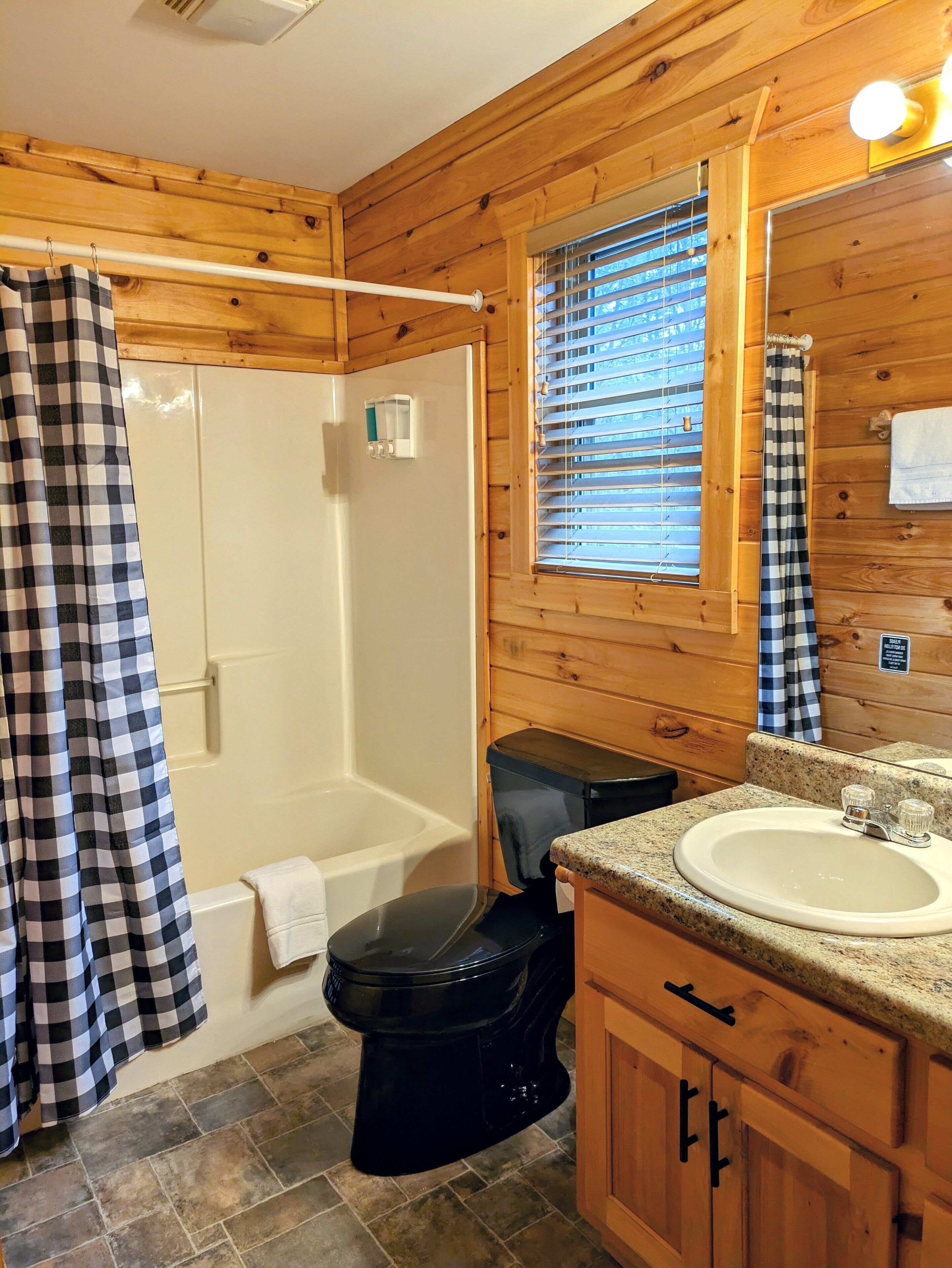 Een houten badkamer in een vakantiehuisje, met douche, toilet en wastafel.