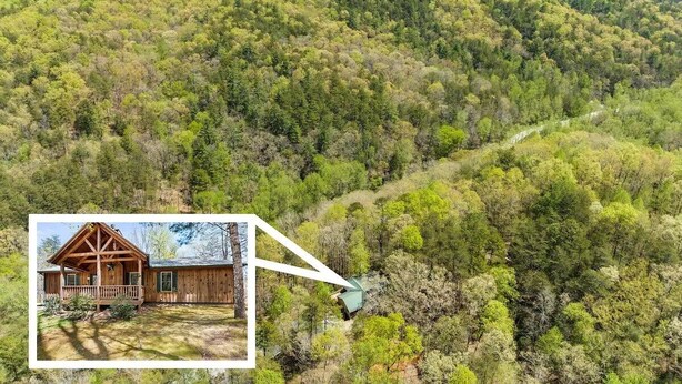 A cabin in a forested area with a view of the surrounding hills.