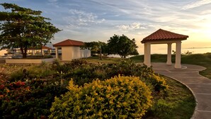 A garden with a gazebo, a small pavilion, and a pathway leading to a body of water. -   ROPER'S PLACE...Bayfront apartment/Balcony view Close to Kingston/Airport
 (Portmore)