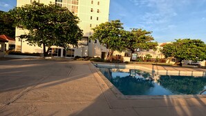 A pool area with a clear view of a building in the background. -   ROPER'S PLACE...Bayfront apartment/Balcony view Close to Kingston/Airport
 (Portmore)
