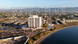 A coastal hotel with a central building, a parking area, and a beach view. -   ROPER'S PLACE...Bayfront apartment/Balcony view Close to Kingston/Airport
 (Portmore)