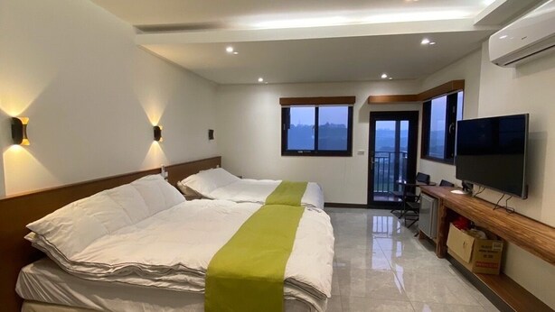 Een hotelkamer met een groot bed, een televisie en uitzicht op de stad.