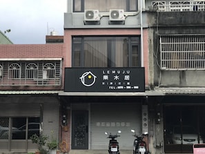 Welcome to LeMUJU, a functional commercial building with a metal gate entrance and parking area.