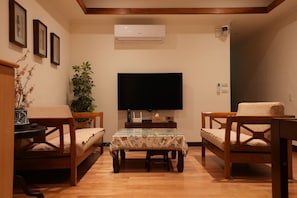 Relax in this stylish living room with a flat-screen TV, comfortable armchairs, and a cozy coffee table.