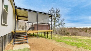 A house with a covered outdoor deck, a staircase leading to a second level, and a fenced yard. - Hudson Oaks Country Creekside Home: Hot Tub & Deck (Weatherford)