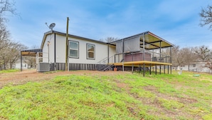 A two-story house with a covered patio and a fenced yard. - Hudson Oaks Country Creekside Home: Hot Tub & Deck (Weatherford)