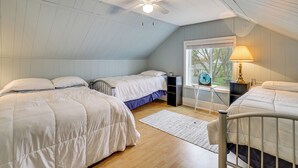 Ein Schlafzimmer mit zwei Betten, einem Deckenventilator, einem Fenster mit Blick und einer Lampe.