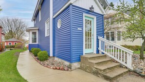 Ein zweigeschossiges Haus mit blauer Fassade, einer weißen Haustür und einer kleinen Veranda mit Stufen.