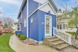 A two-story house with a blue exterior, a white front door, and a small porch with steps. - Ludington Home w/ 6 Bicycles < 1 Mi to Beach! (Ludington)