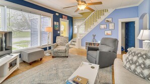 Ein Wohnzimmer mit Deckenventilator, Treppe und blauer Wand.