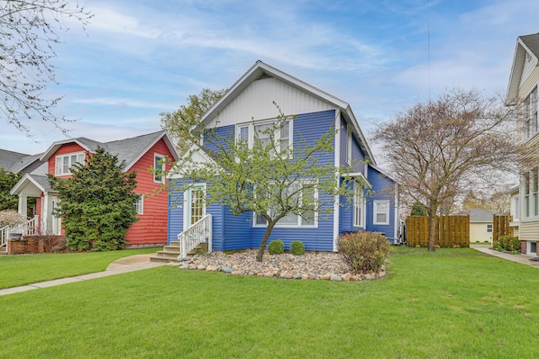A residential house with a sloped roof, a front porch, and a small front yard with a tree and a rock border.
