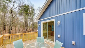 A blue building with a deck, glass sliding doors, and a table with chairs. - Catskills Winter Getaway w/ Game Room (Greenville)