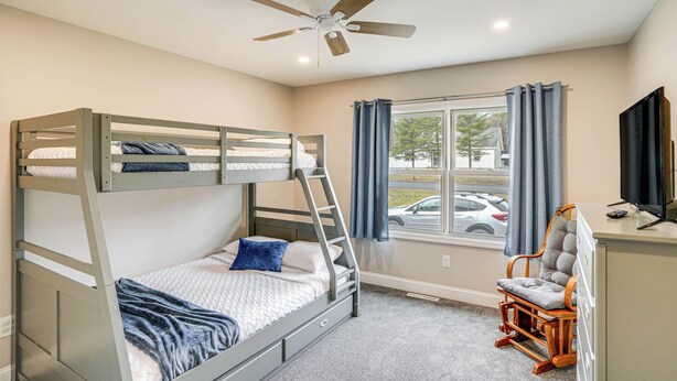 A bunk bed room with a desk and chair, a ceiling fan, and a window with curtains. - Catskills Winter Getaway w/ Game Room (Greenville)