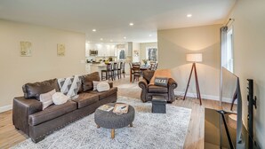 A modern living room with a brown leather sofa, ottoman, and a dining area in the background. - Catskills Winter Getaway w/ Game Room (Greenville)