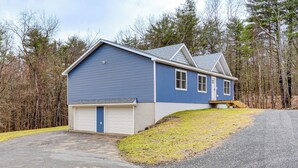 A two-story blue house with a white garage door, a front porch, and a driveway leading to the garage. - Catskills Winter Getaway w/ Game Room (Greenville)