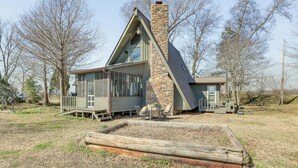 A modern house with a stone chimney, large windows, and a deck. - Boat Dock on Reelfoot Lake: Tiptonville Retreat (Tiptonville)