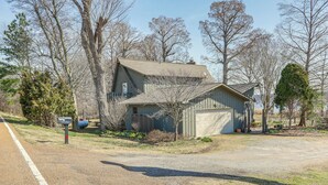 A two-story house with a garage, surrounded by trees and a gravel driveway. - Boat Dock on Reelfoot Lake: Tiptonville Retreat (Tiptonville)