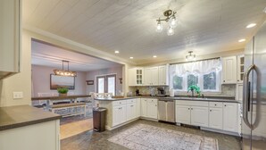 A modern kitchen with white cabinets, a stainless steel refrigerator, and a large island with a sink.