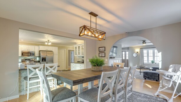 A spacious kitchen with white cabinetry, a wooden dining table, and a chandelier.