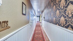 A hallway with a patterned carpet, white wainscoting, and a sign on the left. - Smethport Vacation Rental w/ Fireplace & Lake View (Smethport)