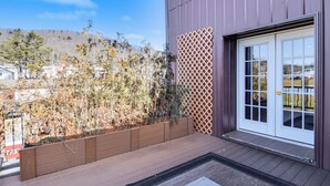A modern building with a wooden deck, a white door with glass panels, and a view of a hilly landscape. - Smethport Vacation Rental w/ Fireplace & Lake View (Smethport)