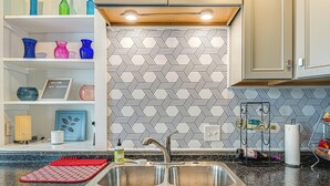 Una cocina con un lavamanos doble, una tabla de cortar roja y un salpicadero decorado.