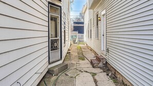 Un estrecho callejón entre dos casas blancas, con una puerta visible y escalones que conducen a la entrada.