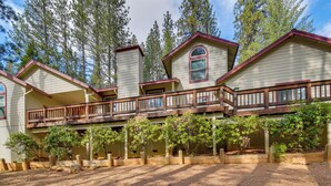 A two-story house with a balcony, surrounded by trees and a wooden deck. - Hot Tub + Pool Table: Cabin Near Calaveras Park! (Arnold)
