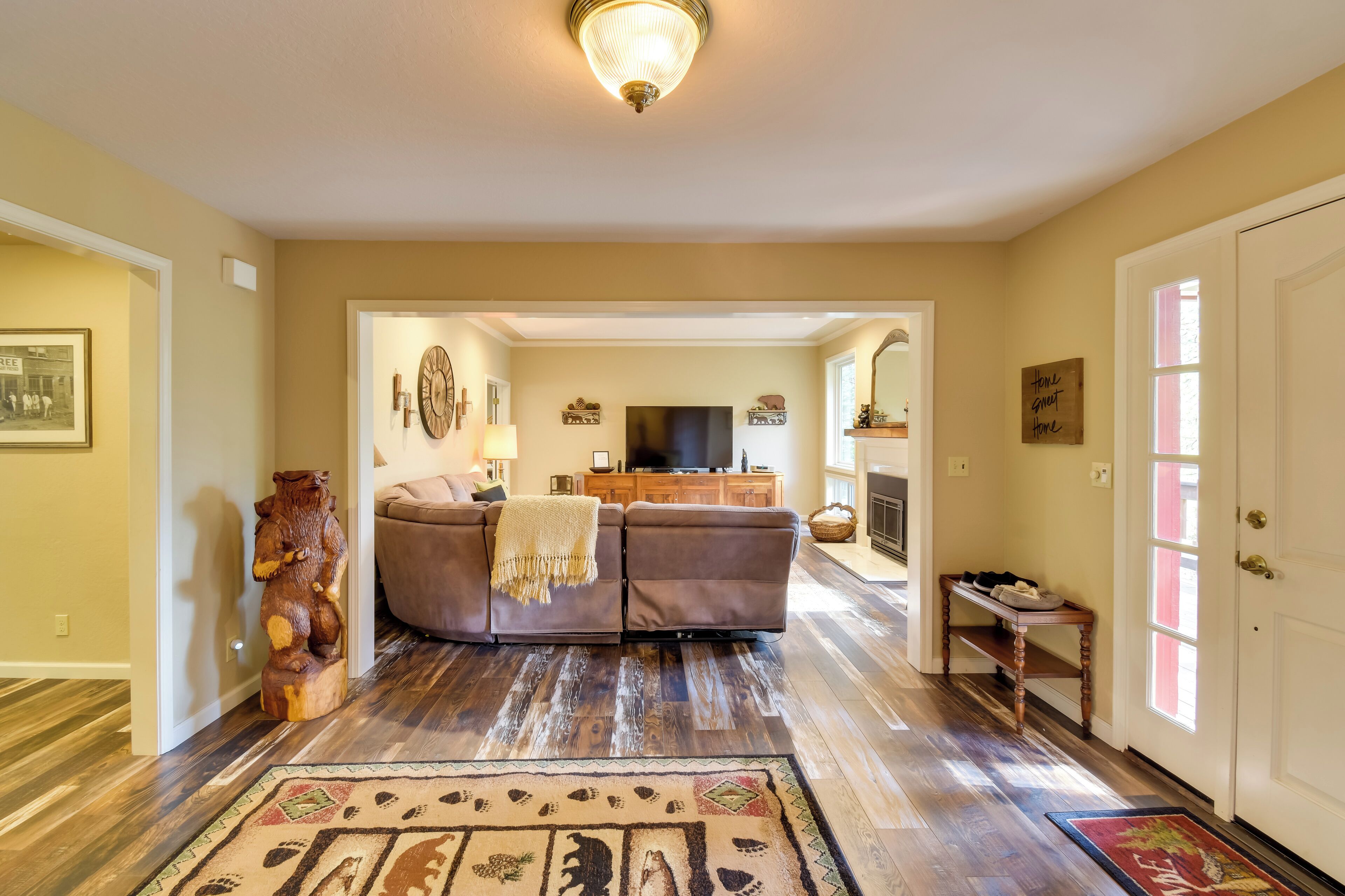A living room with a brown sofa, a wooden bear sculpture, and a television.