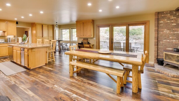 A spacious kitchen with wooden cabinets, a large island, and a dining area with a wooden bench. - Hot Tub + Pool Table: Cabin Near Calaveras Park! (Arnold)