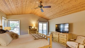 A bedroom with a wooden ceiling, a bed with a headboard, a TV, a chair, and a dresser. - Hot Tub + Pool Table: Cabin Near Calaveras Park! (Arnold)
