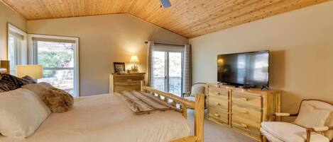 A bedroom with a wooden ceiling, a bed with a headboard, a TV, a chair, and a dresser.