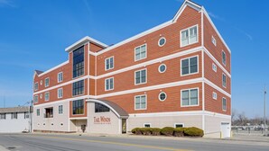 Un edificio de varios pisos con fachada de ladrillo rojo, ventanas grandes y un letrero que dice "Tail Winds Condominiums".