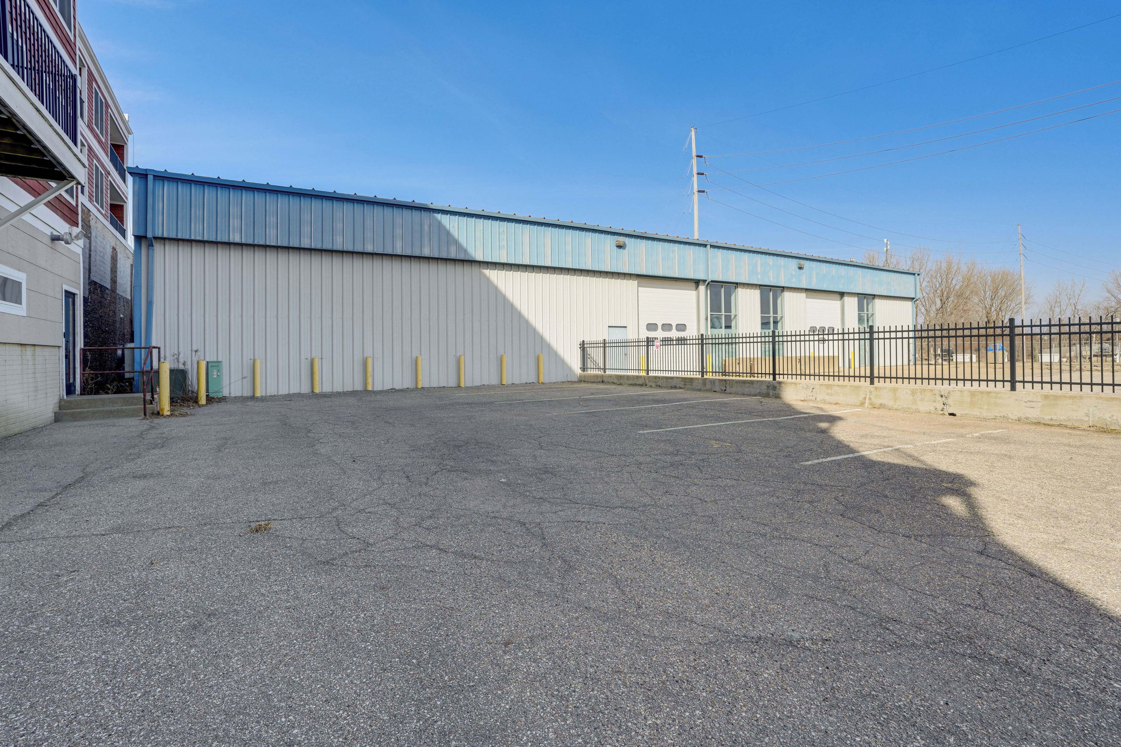 A large industrial building with a flat roof and a fenced parking area.