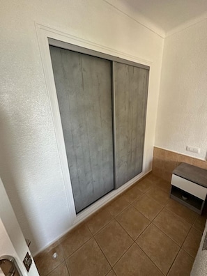 Une pièce dotée d’une porte coulissante, d’un petit placard et d’un revêtement de sol carrelé.