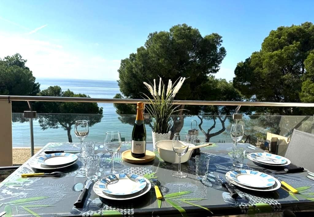 A table set for dining with a view of the sea and trees.