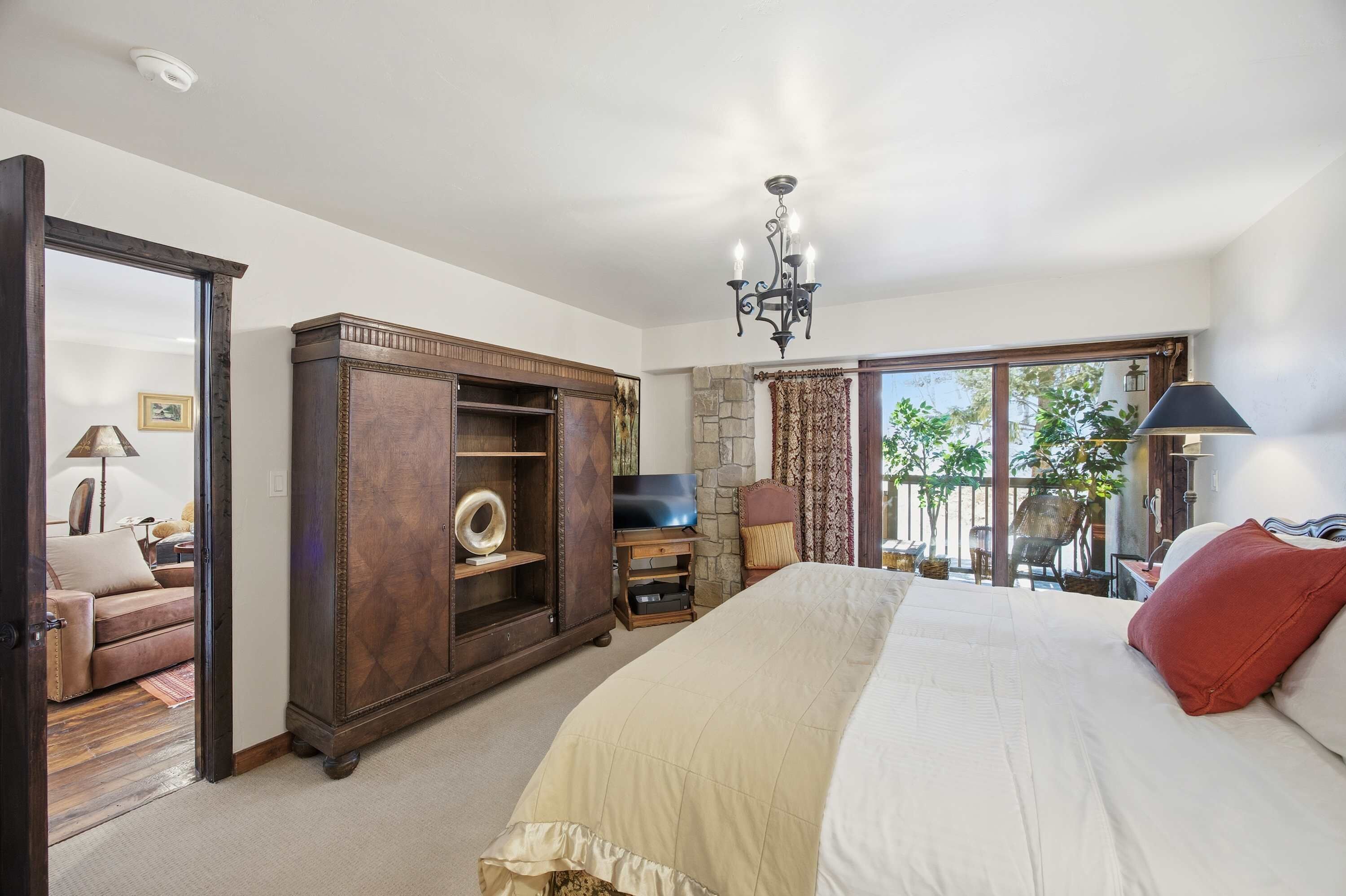 Un dormitorio con una cama grande, un armario, un televisor y vistas al exterior.